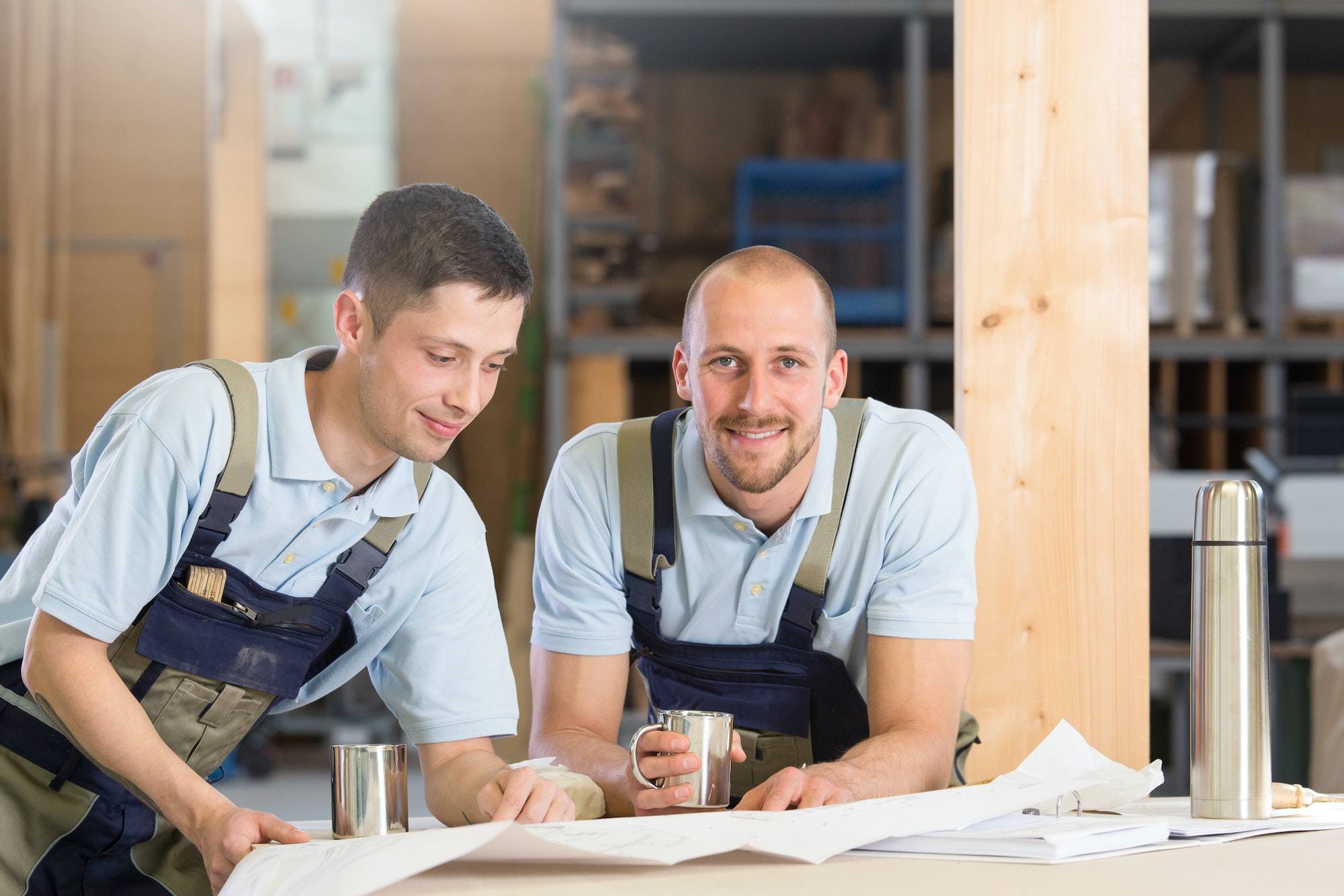 Two craftsmen with metal mugs talking